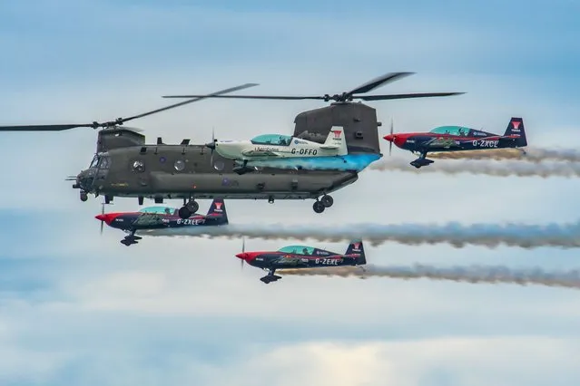 The picture dated August 21st, 2022 shows the RAF Chinook helicopter with the Blade Aerobatic Team at Eastbourne's International Airshow, which returned for its 28th year after back-to-back Covid cancellations. The Spitfire, Typhoon and Wingwalkers were among iconic aircraft from the past and present which flew in the Sussex skies over the four-day event. The show which finished on Sunday evening drew huge crowds along a two-mile stretch in Eastbourne. (Photo by Caroline Haycock/Bav Media)