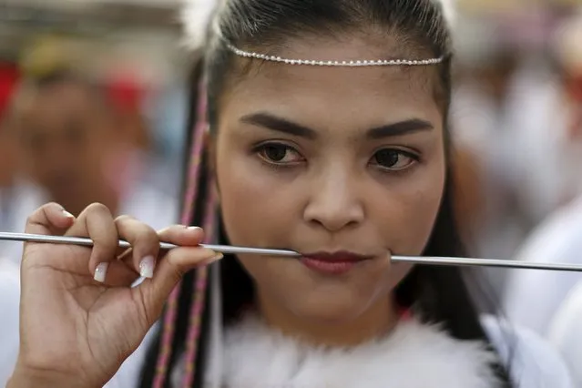 A devotee of the Chinese Jui Tui shrine walks with a spike pierced through her cheeks during a procession celebrating the annual vegetarian festival in Phuket, Thailand October 19, 2015. (Photo by Jorge Silva/Reuters)