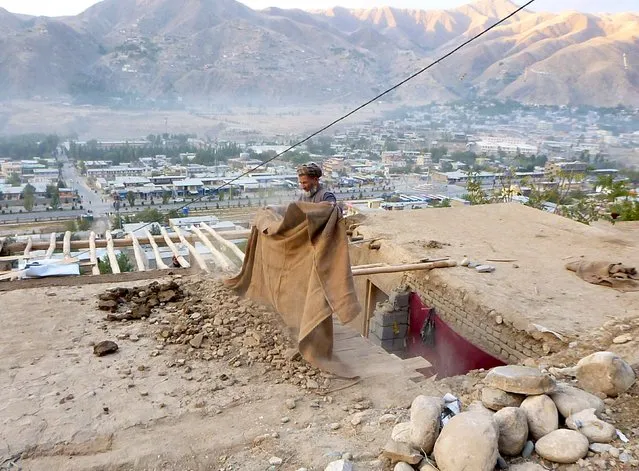 A man clears rubbles from the roof of his house after an earthquake, in Fayzabad capital of Badakhshan province, Afghanistan October 26, 2015. (Photo by Reuters/Stringer)