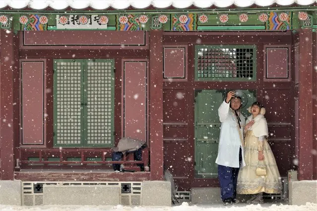 A couple wearing traditional “Hanbok” outfits takes a selfie in the snow at the Gyeongbok Palace, the main royal palace during the Joseon Dynasty and one of South Korea's well known landmarks, in Seoul, South Korea, Thursday, anuary 26, 2023. (Photo by Ahn Young-joon/AP Photo)