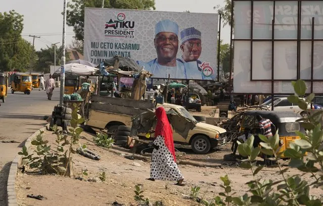 A woman walks past a campaign billboard of Atiku Abubakar, presidential candidate of the People's Democratic Party on the street in Yola, Nigeria Thursday, February 23, 2023. On Feb. 25, voters will choose among 18 candidates in a first-round vote to succeed incumbent President Muhammadu Buhari, but despite being Africa's largest economy and and one of its top oil producers, Nigeria is in economic crisis. (Photo by Sunday Alamba/AP Photo)