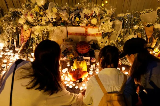 A basketball and a helmet are placed among flowers and candles by pro-democracy supporters as they pay tribute to Chow Tsz-lok, 22, a university student who died after he fell from a car park during a protest one year ago, in Hong Kong, China on November 8, 2020. (Photo by Tyrone Siu/Reuters)