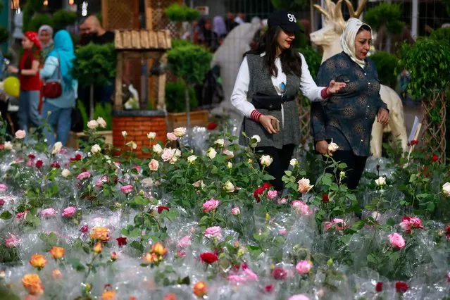 Visitors walk by flower exhibits during the Baghdad International Festival of Flowers and Gardens organized to mark Nowruz celebrations symbolizing the beginning of spring, at the al-Zawraa Zoo in Baghdad on March 16, 2023. (Photo by Ahmad Al-Rubaye/AFP Photo)