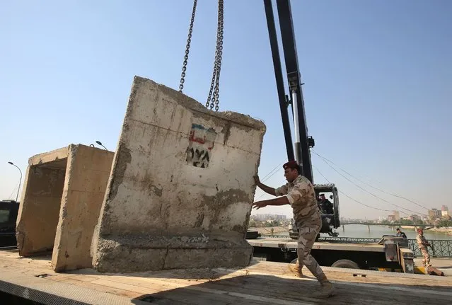 Members of the Iraqi security forces remove concrete blocks on Baghdad's Sinek bridge which was reopened on October 27, 2020 after being closed last week to cut the road leading to the Iranian embassy on the first anniversary of the start of nationwide mass demonstrations against the authorities. Thousands of Iraqis took to the streets nationwide on Octobe 25 to mark the first anniversary of the 2019 revolt dubbed the “October Revolution”, which demanded the ouster of the entire ruling class, accused of ineptitude and corruption. (Photo by Ahmad Al-Rubaye/AFP Photo)