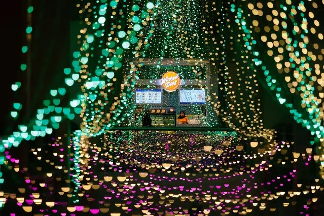 A shopkeeper waits for customers at a stall inside a shopping mall with light decorations installed ahead of the Ramadan festive in Jakarta, Indonesia on March 20, 2023. (Photo by Willy Kurniawan/Reuters)