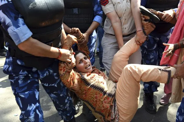 A supporter of opposition Congress party is detained by police while protesting against their leader Rahul Gandhi's expulsion from Parliament in New Delhi, India, Monday, March 27, 2023. Gandhi was expelled from Parliament a day after a court convicted him of defamation and sentenced him to two years in prison for mocking the surname Modi in an election speech. (Photo by Deepanshu Aggarwal/AP Photo)