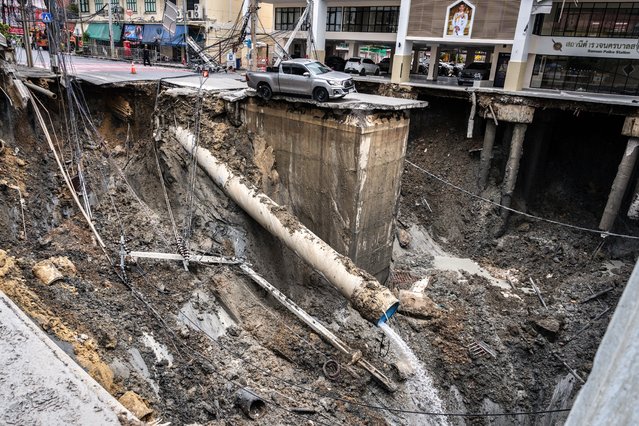 A vehicle is seen on the edge of a hole in the ground after a road collapsed near a hospital in Bangkok on September 24, 2025. A portion of a busy road in Thailand's capital caved in early on September 24, leaving a hole dozens of meters deep in front of a main hospital and forcing people nearby to evacuate. (Photo by Chanakarn Laosarakham/AFP Photo)