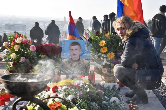 A woman pays respects to a victim of the war over Karabakh, during a gathering for a memorial ceremony, at the Yerablur Military Memorial Cemetery in Yerevan, on December 19, 2020. Armenian Prime Minister Nikol Pashinyan led, on December 19, 2020, thousands in a march in memory of those killed in a six-week war with Azerbaijan as the Caucasus country began three days of mourning. Pashinyan has been under huge pressure from the opposition to step down after nearly 3,000 Armenians were killed in the clashes with Azerbaijan over the breakaway region of Nagorno-Karabakh. (Photo by Karen Minasyan/AFP Photo)