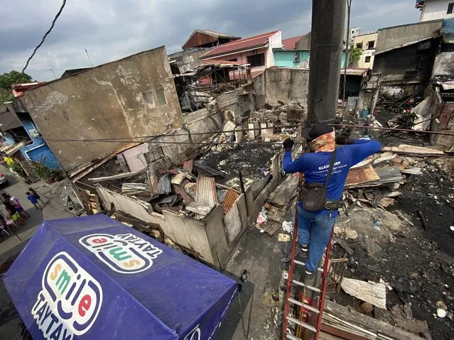 A lineman removes burnt electric wires at the scene of a fire in Taytay city, Metro Manila, Philippines, 10 April 2023. Seven deceased people embracing each other after being trapped were found at the scene of a fire near the Philippines capital. The fire destroyed 40 houses leaving 60 homeless in the densely populated Taytay city. (Photo by Francis R. Malasig/EPA)