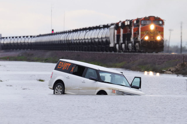 A train passes as floodwaters from the Tule River inundate the area after days of heavy rain in Corcoran, California, U.S., March 22, 2023. (Photo by David Swanson/Reuters)