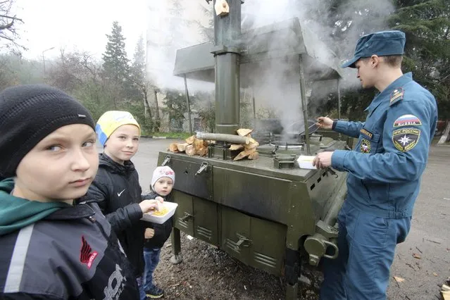 Children visit a mobile station, opened and operated by members of the Russian Emergencies Ministry to lend support and distribute hot meals to local residents due to power cuts in the settlement of Massandra, Crimea, November 27, 2015. (Photo by Pavel Rebrov/Reuters)