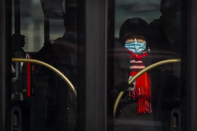 A woman wearing a face mask to protect against the spread of the coronavirus rides a public bus in Beijing, Wednesday, January 20, 2021. China is now dealing with coronavirus outbreaks across its frigid northeast, prompting additional lockdowns and travel bans. (Photo by Mark Schiefelbein/AP Photo)