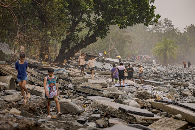 Residents make their way across a highway destroyed by storm surges brought about by Super Typhoon Fung-wong on November 10, 2025 in Dipaculao, Aurora province, Philippines. (Photo by Ezra Acayan/Getty Images)