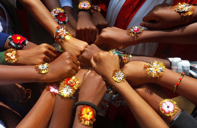 Indian school children show “Rakhi” or sacred thread on their wrists during the Raksha Bandhan festival celebrations at government school in Bangalore, India, 19 August 2024. Raksha Bandhan is a cherished Hindu festival that celebrates the bond between sisters and brothers and on this special day, sisters traditionally tie a Rakhi, a sacred thread, around their brothers' wrists as a symbol of their love and in return for their protection. This festival is widely celebrated across India, transcending caste and creed, with people from all walks of life coming together to honor this enduring and heartwarming tradition. (Photo by Jagadeesh N.V./EPA/EFE)
