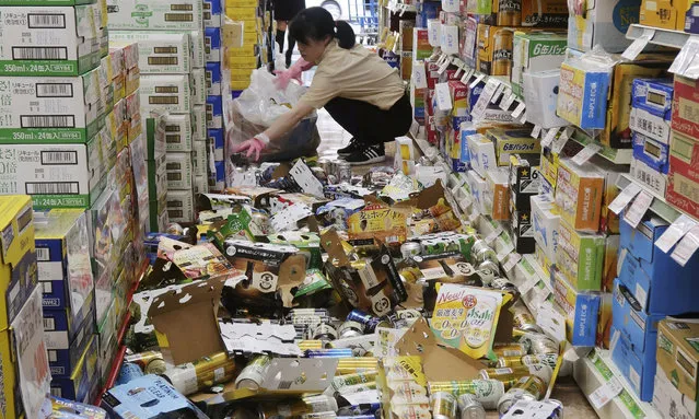 Employees gather bottles and cans scattered by an earthquake in Osaka, Hirakata, Japan on June 18, 2018. (Photo by Kyodo News via Reuters)