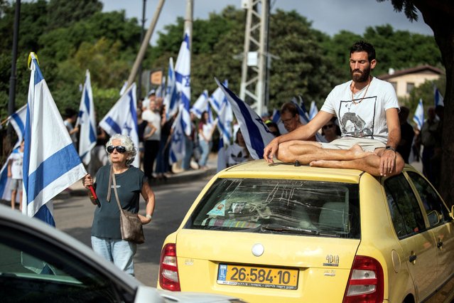A man sits on the roof of a car as people mourn Israeli soldier Sergeant Yoav Agmon, who was killed in a drone attack from Lebanon for which Hezbollah claimed responsibility, during his funeral, amid hostilities between Hezbollah and Israeli forces, in Binyamina-Givat Ada, Israel on October 15, 2024. (Photo by Itay Cohen/Reuters)