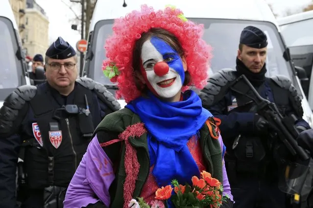 An environmentalist wears a red nose as she demonstrates near French riot police in Paris, France, as the World Climate Change Conference 2015 (COP21) continues at Le Bourget, December 12, 2015. (Photo by Pascal Rossignol/Reuters)