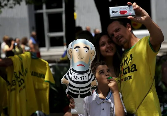 A family pose for a selfie as the boy holds an inflatable doll known as “Pixuleco” of Brazil's former president Luiz Inacio Lula da Silva during a protest calling for the impeachment of Brazil's President Dilma Rousseff in Sao Paulo, Brazil, December 13, 2015. (Photo by Nacho Doce/Reuters)
