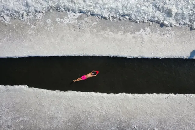 This aerial view shows a man swimming in a pool cut in a frozen lake in Shenyang, in China's northeastern Liaoning province on January 7, 2021. (Photo by AFP Photo/China Stringer Network)