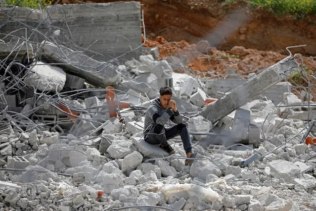 A Palestinian youth sits on the rubble of his family house that was demolished by Israeli forces, in Jordan Valley in the Israeli-occupied West Bank on March 10, 2021. (Photo by Raneen Sawafta/Reuters)