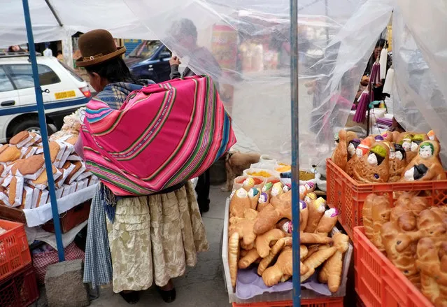 A woman stands next to “T'antawawas” (children's bread) in a popular market to commemorate All Saints Day in La Paz, October 30, 2016. (Photo by David Mercado/Reuters)