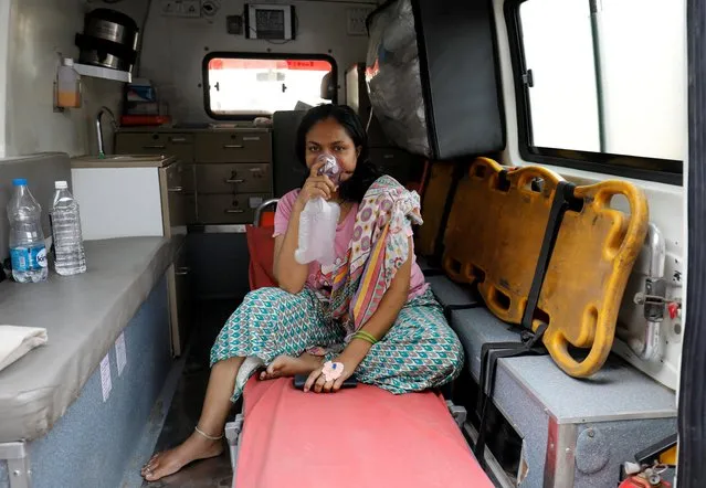 A patient with breathing problems wears an oxygen mask as she waits inside an ambulance in a queue to enter a COVID-19 hospital, amidst the coronavirus disease pandemic, Ahmedabad, India, April 14, 2021. (Photo by Amit Dave/Reuters)