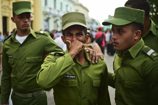 Soldiers cry after the urn with the ashes of Cuban leader Fidel Castro was driven through Santa Clara on December 1, 2016 during its four-day journey across the island for the burial in Santiago de Cuba. A military jeep is taking the ashes of Fidel Castro on a four-day journey across Cuba, with islanders lining the roads to bid farewell to the late communist icon. Castro died at 90 on November 25, 2016 and will be buried in the eastern city of Santiago de Cuba on Sunday. (Photo by Ronaldo Schemidt/AFP Photo)