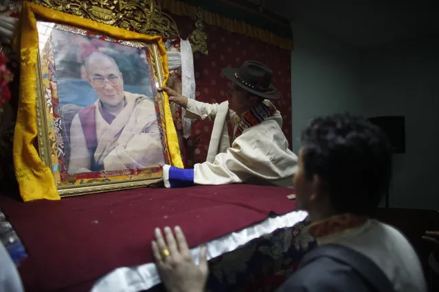 Tibetan men place a portrait of spiritual leader the Dalai Lama on a raised stage during Tibetan New Year, or Losar, inside the Tibetan Refugee Camp in Lalitpur, Nepal, Thursday, February 19, 2015. (Photo by Niranjan Shrestha/AP Photo)