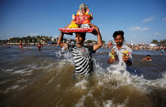 A devotee carries an idol of the Hindu god Ganesh, the deity of prosperity, to immerse into the Arabian Sea on the fifth day of Ganesh Chaturthi festival in Mumbai, India, September 17, 2018. (Photo by Francis Mascarenhas/Reuters)