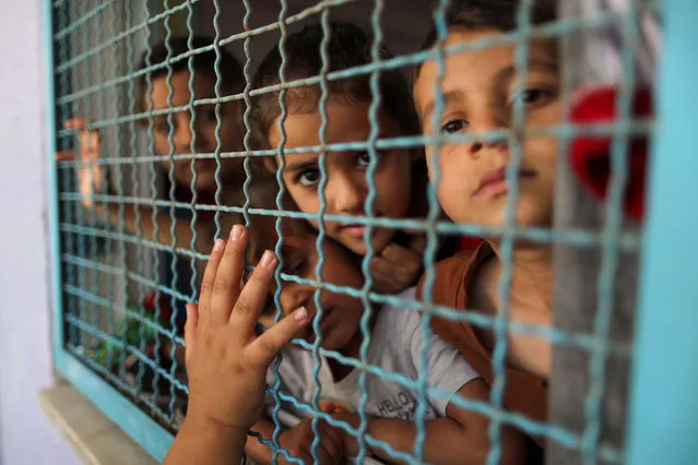 Palestinian children, who fled their homes due to Israeli air and artillery strikes, look through a window fence at a United Nations-run school where they take refuge, in Gaza City on May 18, 2021. (Photo by Suhaib Salem/Reuters)