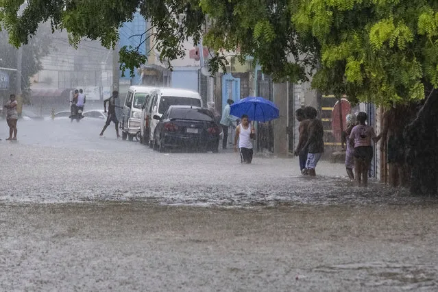 People walk through a street flooded by the rains of Tropical Storm Franklin in Santo Domingo, Dominican Republic, Tuesday, August 22, 2023. (Photo by Ricardo Hernandez/AP Photo)