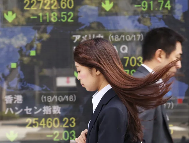 People walk by an electronic stock board of a securities firm in Tokyo, Thursday, October 18, 2018. Shares fell Thursday in Asia after a retreat on Wall Street driven by a sell-off of technology shares, homebuilders and retailers. A report of weaker Japanese exports in September underscored uncertainties over the outlook for trade. (Photo by Koji Sasahara/AP Photo)