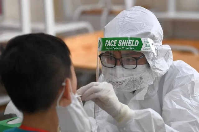 A health worker wearing personal protective equipment (PPE) conducts a Covid-19 coronavirus swab test on a student at the Vinschool private school in Hanoi on May 22, 2021. (Photo by Nhac Nguyen/AFP Photo)
