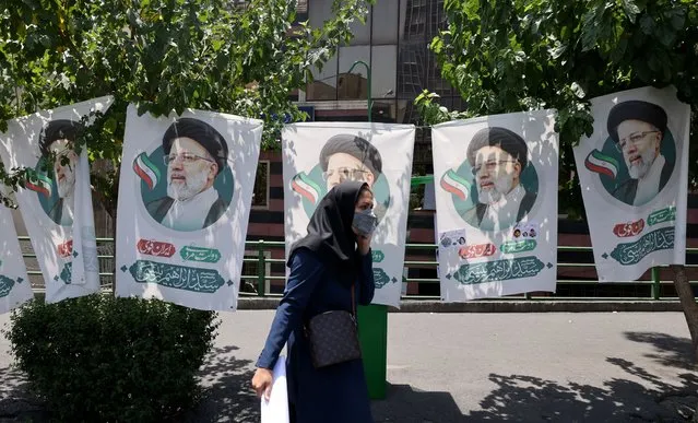 An Iranian woman walks past banners of ultraconservative cleric and presidential candidate Ebrahim Raisi, in Tehran, on June 17, 2021, on the eve of the Islamic republic's presidential election. (Photo by Atta Kenare/AFP Photo)