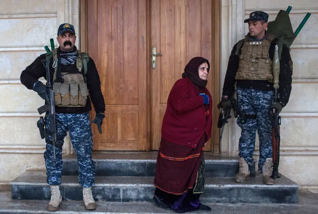 Under heavy security a woman leaves the Mar Hanna church after attending Christmas day mass in Qaraqosh on December 25, 2016 in Mosul, Iraq. The predominantly Christian towns of Bartella and Qaraqosh on the outskirts of Mosul were recently liberated from ISIL as part of the Mosul offensive. The towns were heavily damaged and churches burned and defaced while under ISIL control. Christian communities around Mosul are celebrating Christmas Day as the Mosul offensive continues. (Photo by Chris McGrath/Getty Images)