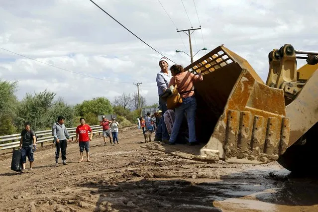 People are transported on an excavator as they are evacuated from their home at Copiapo city, March 26, 2015. (Photo by Ivan Alvarado/Reuters)