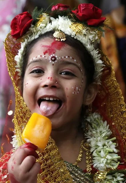 A young Hindu girl eats an ice-cream before participating in a ceremony where she and other girls  will be worshipped as “Kumari”, or living goddess, during Ram Navami festival, at a temple in Kolkata, India, Saturday, March 28, 2015. (Photo by Bikas Das/AP Photo)