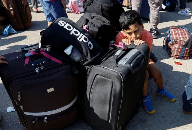 A child rests on luggage as Palestinians with dual citizenship gather outside Rafah border crossing with Egypt in the hope of getting permission to leave Gaza, amid the ongoing Israeli-Palestinian conflict, in Rafah in the southern Gaza Strip on October 16, 2023. (Photo by Ibraheem Abu Mustafa/Reuters)