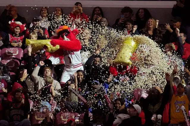 The Chicago Bulls mascot Benny The Bulls pours a complete bag of popcorn on fans during a break in the action in the first half of an NBA basketball game between the Bulls and the Utah Jazz Monday, November 6, 2023, in Chicago. (Photo by Charles Rex Arbogast/AP Photo)