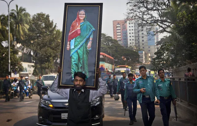 A supporter of Bangladesh Awami League party carries a huge photograph of Bangladesh Prime Minister Sheikh Hasina during an election rally in Dhaka in Bangladesh, Thursday, December 27, 2018. Bangladesh heads for the 11th National Parliamentary Election on Dec. 30, amid opposition allegations that thousands of its leaders and activists have been arrested to weaken them. But authorities say the arrests are not politically motivated and the opposition is trying to create chaos ahead of elections. (Photo by Anupam Nath/AP Photo)