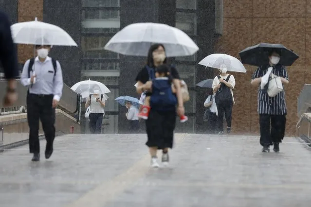 People make their way in a rain affected by a tropical storm in Sendai, Miyagi prefecture, northeast of Tokyo Wednesday, July 28, 2021. Nepartak, the season's eighth typhoon for Japan, brought strong winds and heavy rain to Japan's northern coast Wednesday after moving away from the Tokyo region and relieving the Olympic host city of a feared disruption to the games. (Photo by Kyodo News via AP Photo)