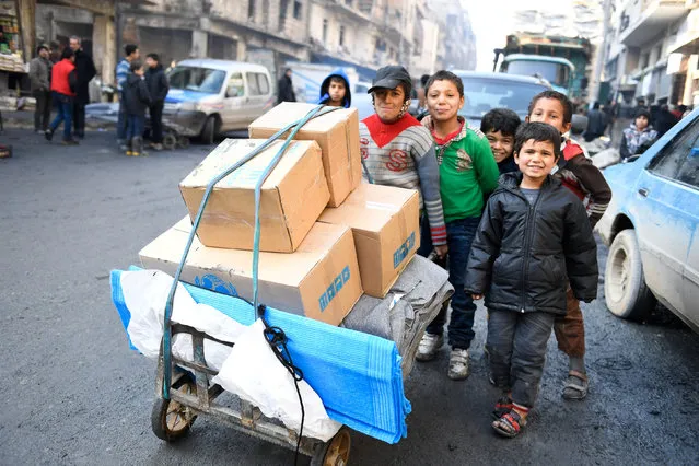 Children push a cart carrying relief items provided by UNHCR and other UN partners in the east Aleppo neighborhood of Tariq al-Bab, in this handout picture provided by UNHCR on January 4, 2017. (Photo by Bassam Diab/Reuters)