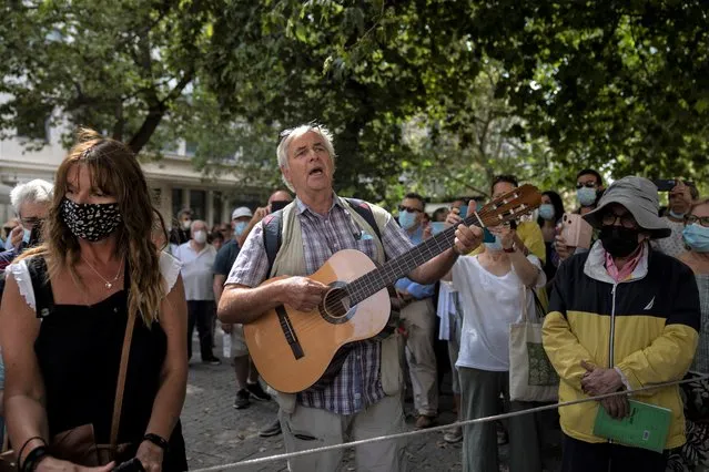 A man plays guitar outside the Athens Cathedral in Athens on Monday September 6, 2021. Hundreds of people have gathered outside Athens Cathedral where Greek composer and politician Mikis Theodorakis is to lie in state in a chapel of the cathedral for three days ahead of his burial on the southern island of Crete. (Photo by Petros Giannakouris/AP Photo)