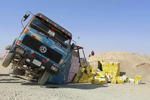 An Afghan driver stands amid boxes of dry food next to his damaged truck at the site of an accident near the Pakistan-Afghanistan border crossing point in Chaman, Pakistan on August 20, 2021. (Photo by AFP Photo/Stringer Network)