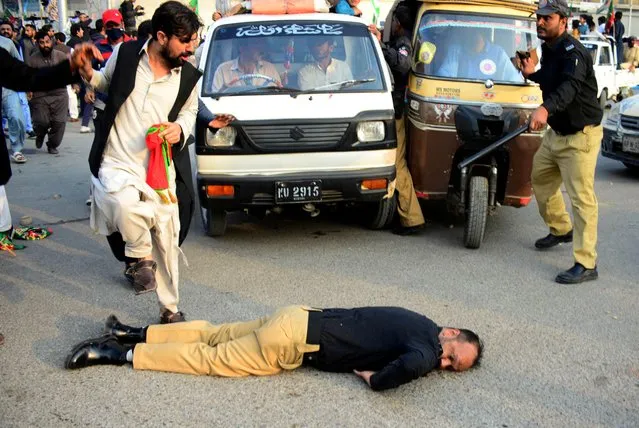 An injured police officer lies on the road during a clash with supporters of former prime minister Imran Khan's party, the Pakistan Tehreek-e-Insaf (PTI), at a rally ahead of a general election, in Karachi, Pakistan, on January 28, 2024. (Photo by Reuters/Stringer)