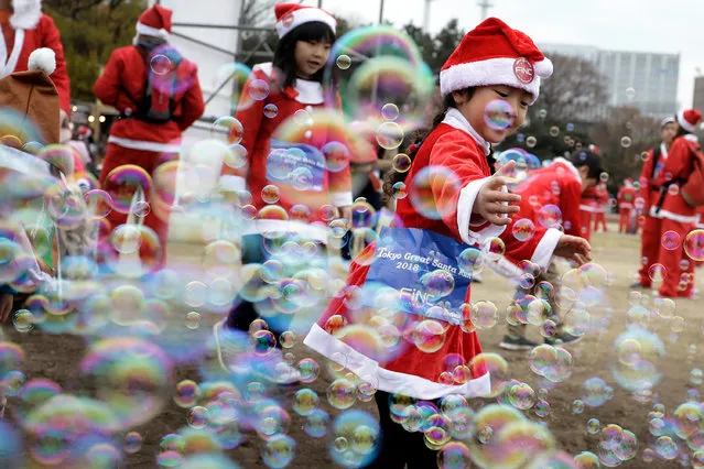 A girl dressed in a Santa Claus costume plays with bubbles prior to the Tokyo Great Santa Run 2018 in Tokyo, Japan, 23 December 2018. Some 2,500 participants took part in the event. (Photo by Kiyoshi Ota/EPA/EFE)