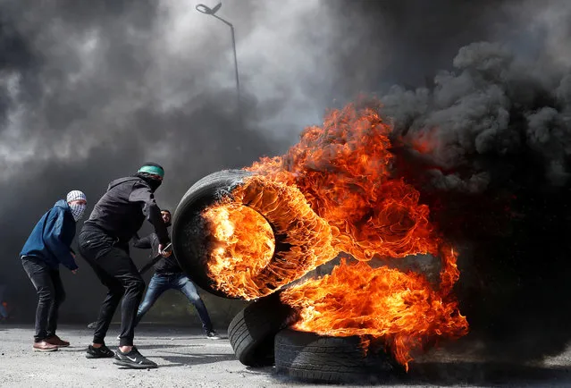 A Palestinian protester moves a burning tire during clashes with Israeli troops near the Jewish settlement of Beit El, in the Israeli-occupied West Bank March 27, 2019. (Photo by Mohamad Torokman/Reuters)