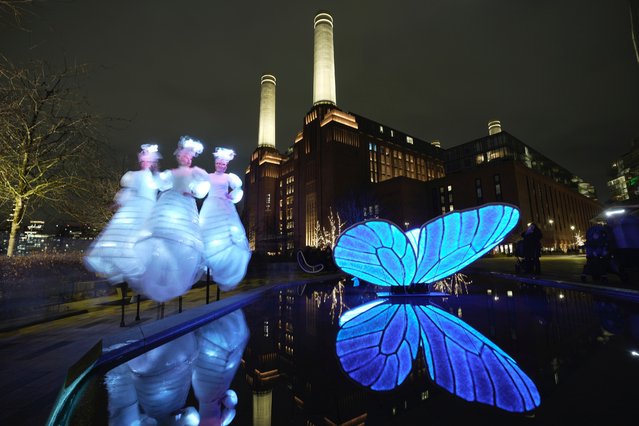 Performers walk past a light installation “Butterfly Effect” designed by Japan artist Masamichi Shimada, at the Battersea Power Station in London, Thursday, January 25, 2024. The Light Festival involved seven light installations from British and international artists at Battersea Power Station, which illuminated the winter evenings between Jan. 25 and Feb, 25. (Photo by Kin Cheung/AP Photo)