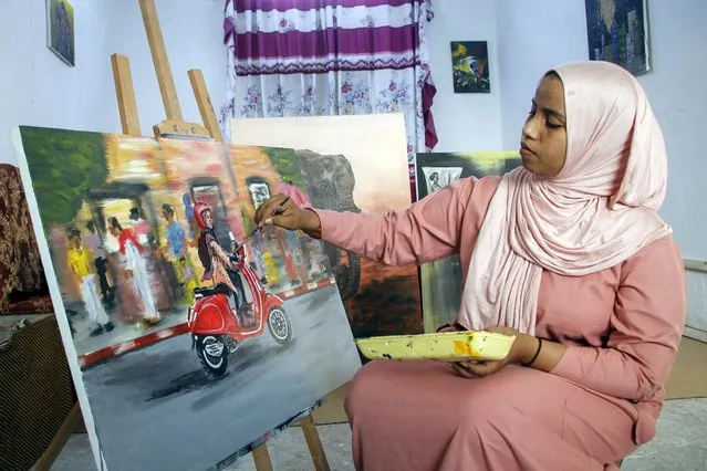 Somali artist Sana Ashraf Sharif Muhsin, 21, works on one of her paintings at her home in the capital Mogadishu, Somalia Friday, October 15, 2021. Among the once-taboo professions emerging from Somalia's decades of conflict and Islamic extremism is the world of arts, and this 21-year-old female painter has faced more opposition than most. (Photo by Farah Abdi Warsameh/AP Photo)