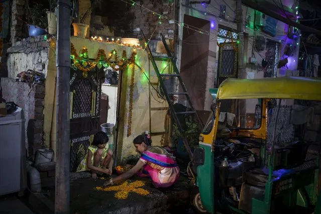 A woman and her daughter make a rangoli, a traditional decoration, at the entrance to their home during Diwali celebrations in New Delhi, India, Thursday, November 4, 2021. Diwali, the festival of lights, is one of Hinduism's most important festivals dedicated to the worship of Lakshmi, the Hindu goddess of wealth. (Photo by Altaf Qadri/AP Photo)